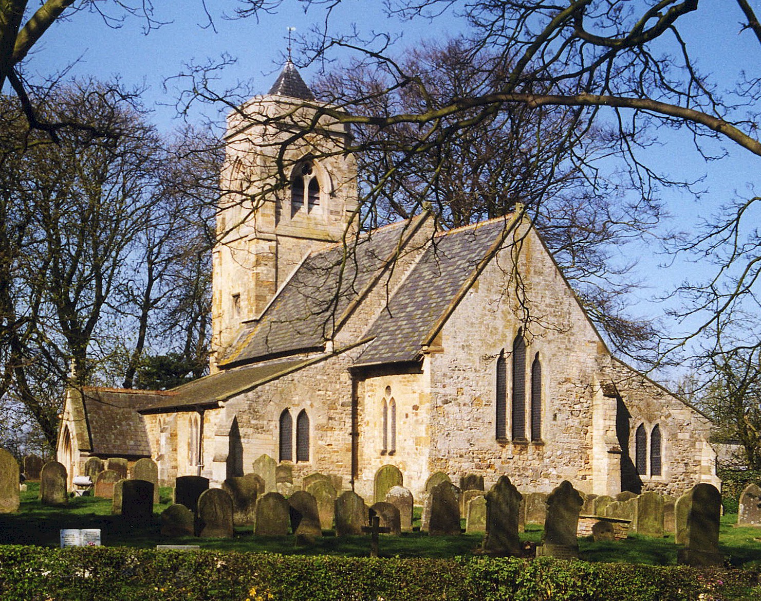 St Nicholas Church, North Cotes — historic limestone church with tower, viewed through bare tree branches